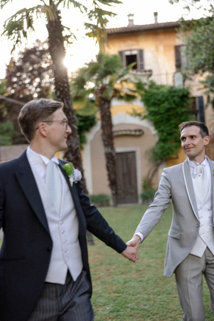 due sposi omosessuali che si tengono per mano, con sfondo villa storica